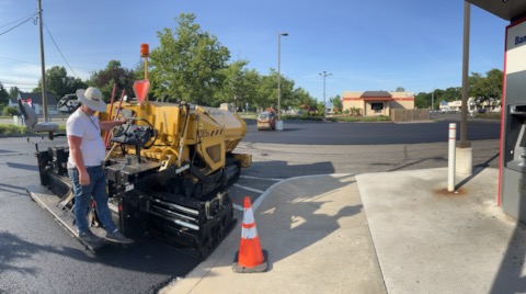 Commercial asphalt paving machine working near traffic cones