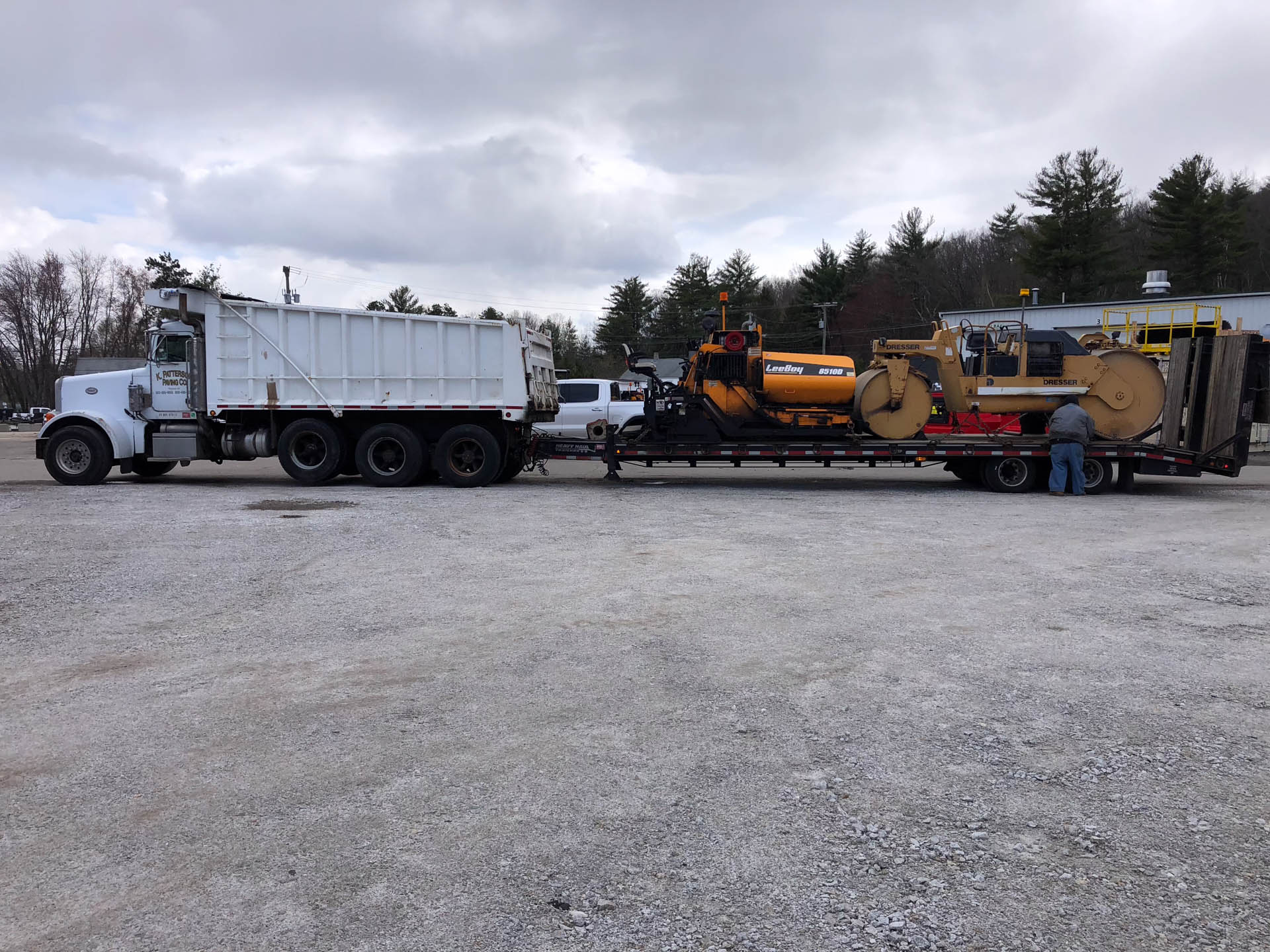 Industrial asphalt paving equipment transported on construction trailer