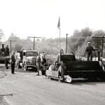 Vintage asphalt paving machine and road construction crew